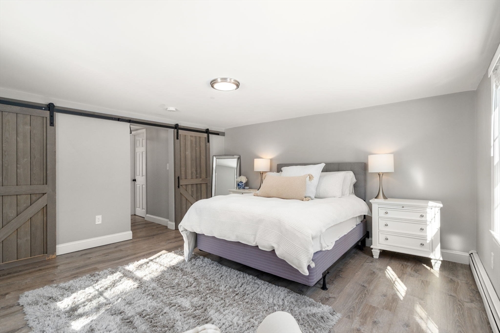 738 Whiting Street Hanover, MA 02339 - Photo 10 of 32 a spacious bedroom with a bed and a lamp