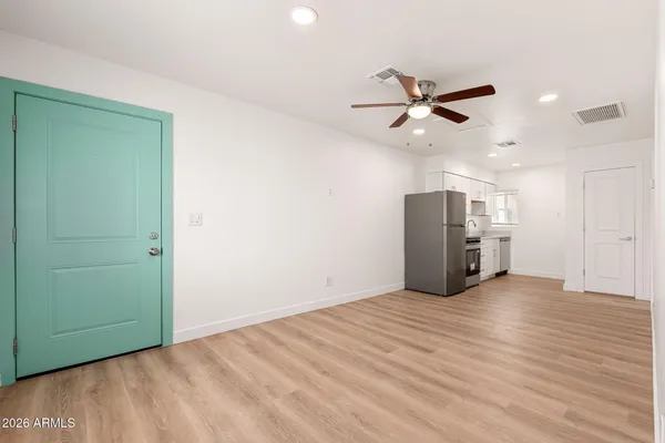 an empty room with wooden floor a ceiling fan white walls and windows