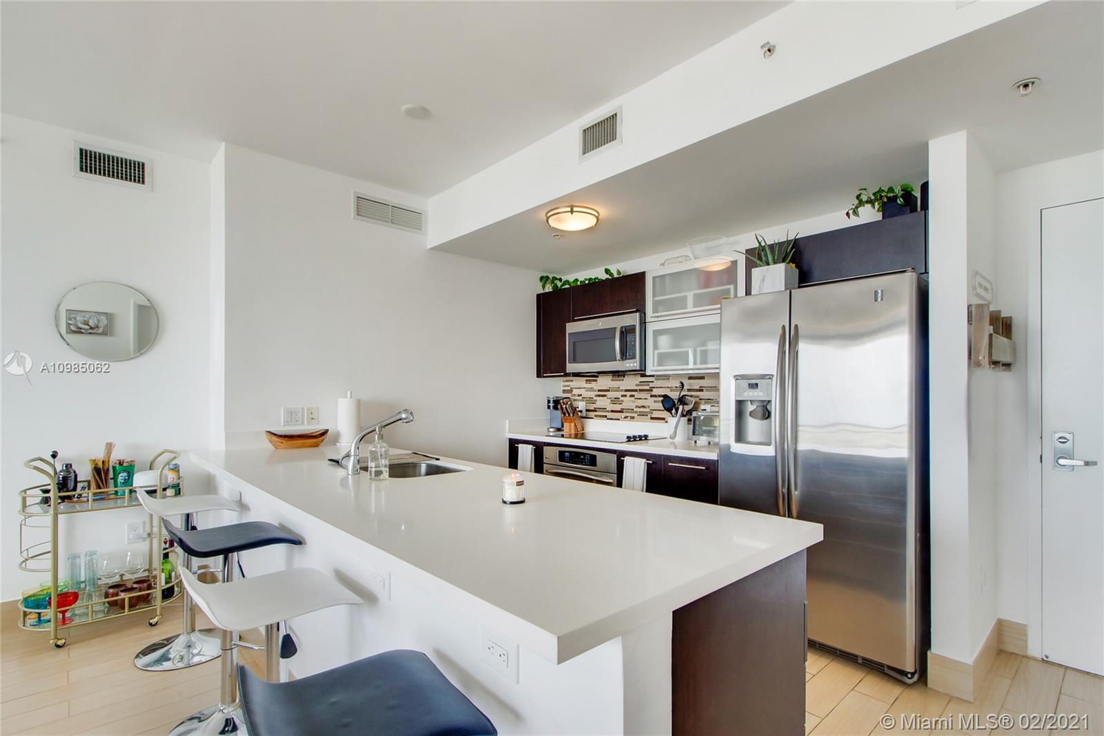 90 Southwest 3rd Street, Unit 2406 Miami, FL 33130 - Photo 2 of 12 a kitchen with a refrigerator a sink and chairs
