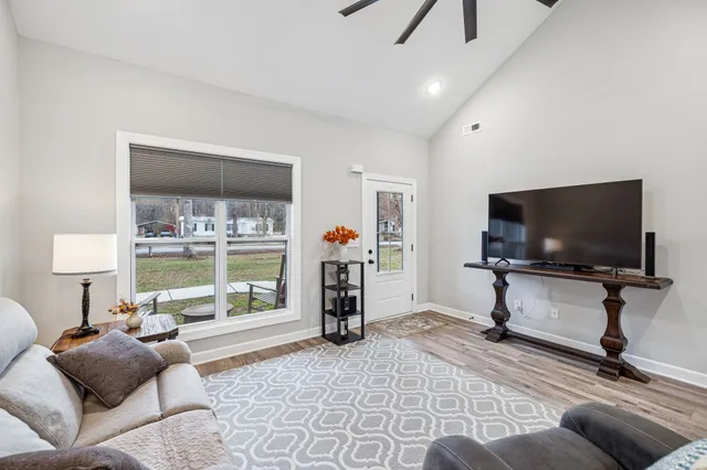 a kitchen with stainless steel appliances kitchen island granite countertop a refrigerator a stove top oven a sink dishwasher and white cabinets with wooden floor