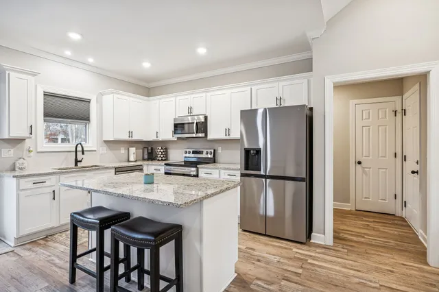 a kitchen with kitchen island a refrigerator a stove a dining table and chairs