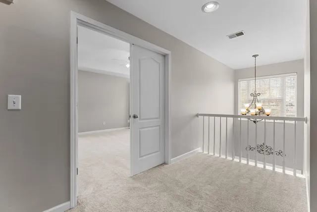a view of an empty room with chandelier fan and windows