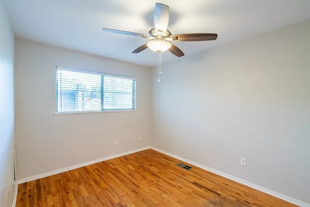 an empty room with a window and ceiling fan