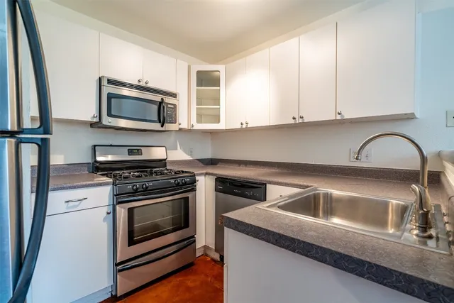 a kitchen with stainless steel appliances granite countertop a stove microwave and sink