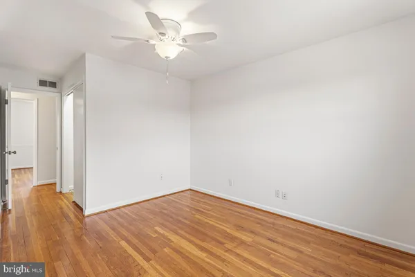 an empty room with wooden floor and fan