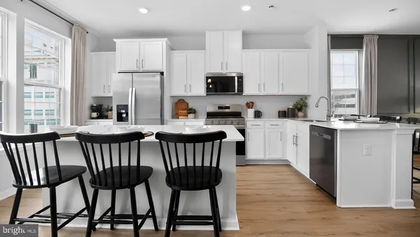 a kitchen with stainless steel appliances a table chairs microwave and sink
