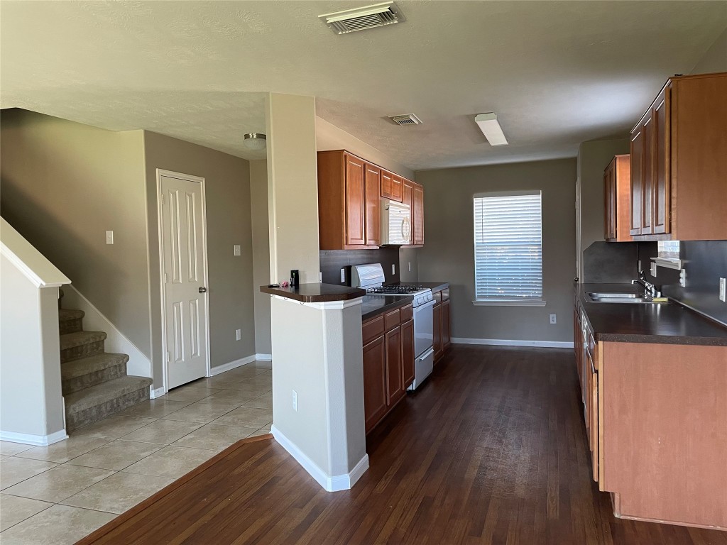 8103 Katie Mill Trail Spring, TX 77379 - Photo 23 of 36 a kitchen with granite countertop wooden floors and white stainless steel appliances