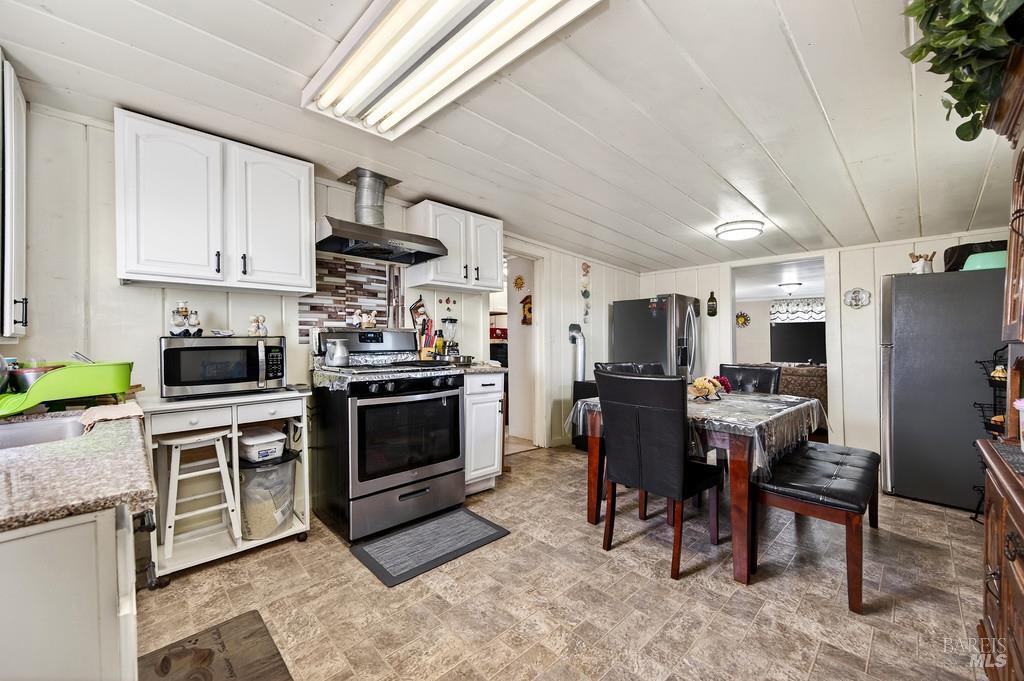 3834 Highway 84 Walnut Grove, CA 95690 - Photo 81 of 84 a kitchen with stainless steel appliances granite countertop a stove top oven a sink dishwasher a dining table and chairs with wooden floor