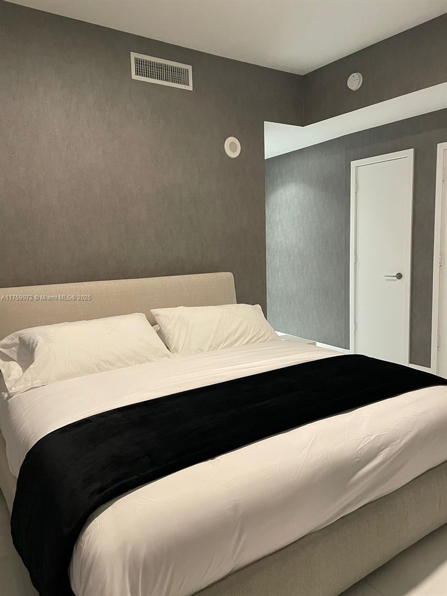851 Northeast 1st Avenue, Unit 1401 Miami, FL 33132 - Photo 12 of 38 a bedroom with a bed and a night stand