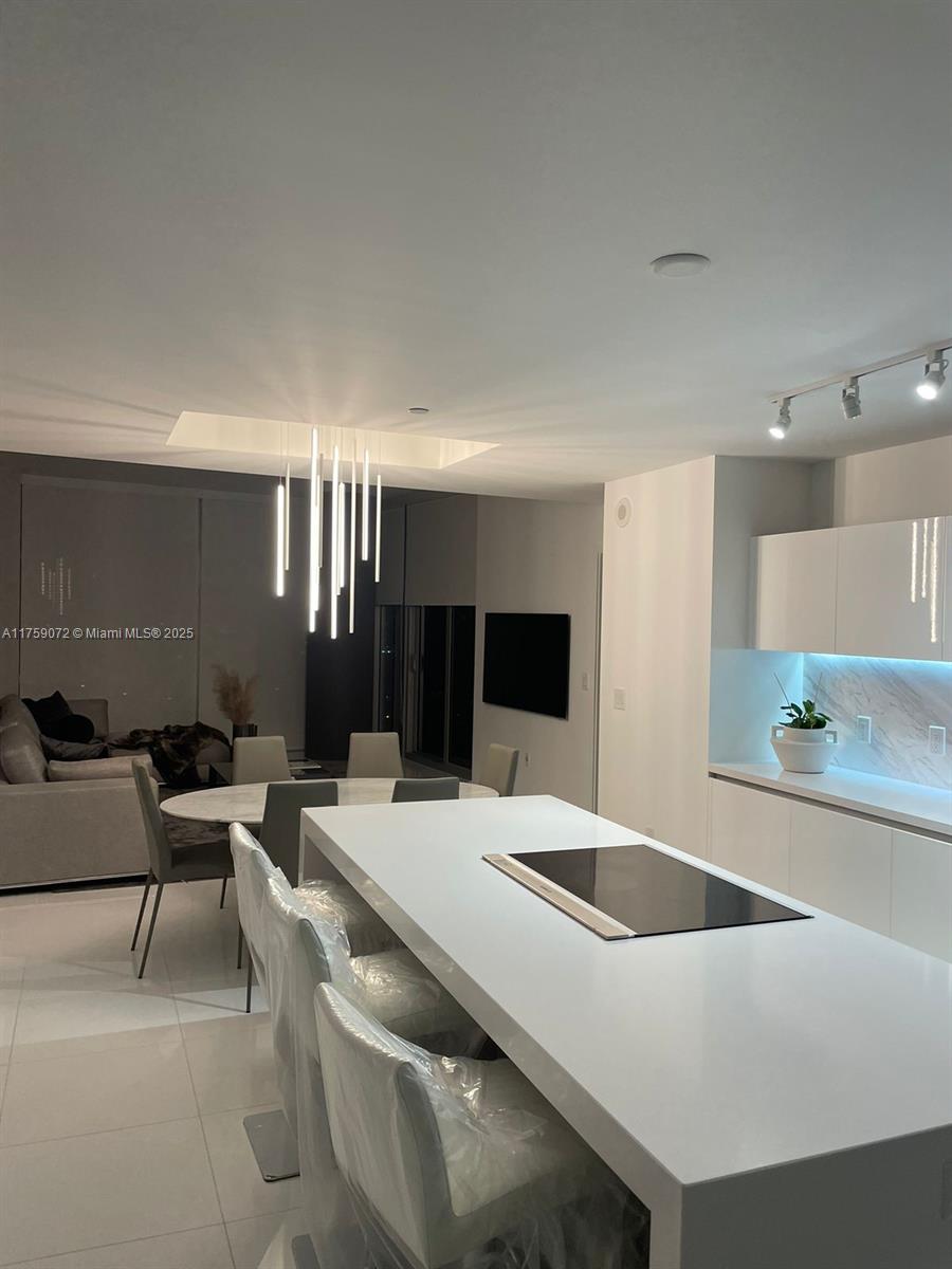 851 Northeast 1st Avenue, Unit 1401 Miami, FL 33132 - Photo 5 of 38 a kitchen with a table chairs sink and white cabinets