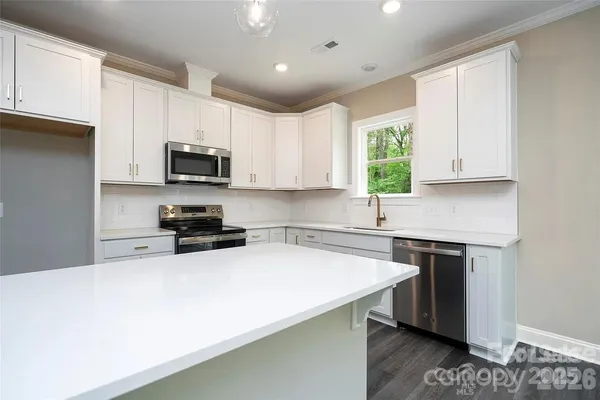 a kitchen with a sink a microwave a stove and cabinets