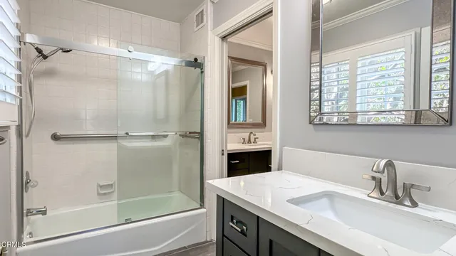 a bathroom with a shower sink vanity and mirror