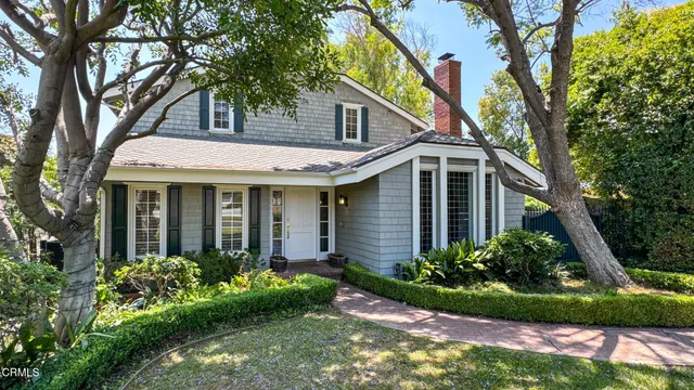 a view of a white house next to a yard with plants and trees
