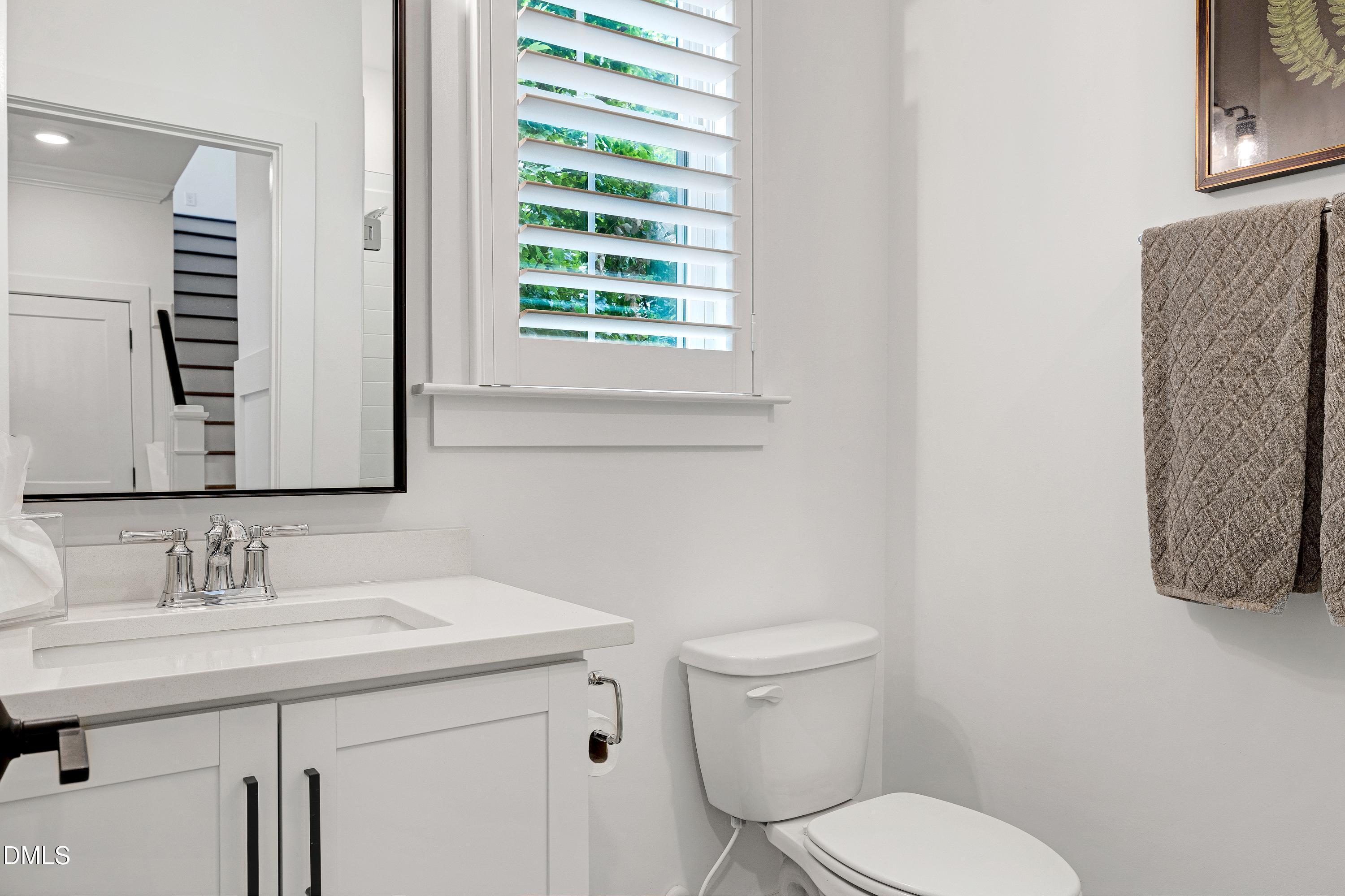 400 Bryan Pointe Drive, Unit 104 Raleigh, NC 27608 - Photo 16 of 66 a bathroom with a toilet a sink a mirror and a window