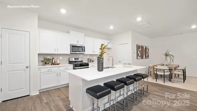 a open kitchen with granite countertop a sink and white cabinets
