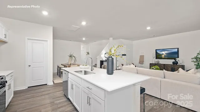 a kitchen with a sink and white cabinets with wooden floor