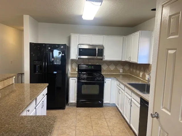 a kitchen with granite countertop white cabinets and stainless steel appliances