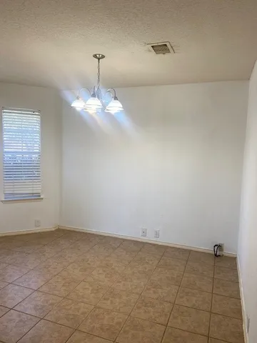 an empty room with a chandelier fan and windows