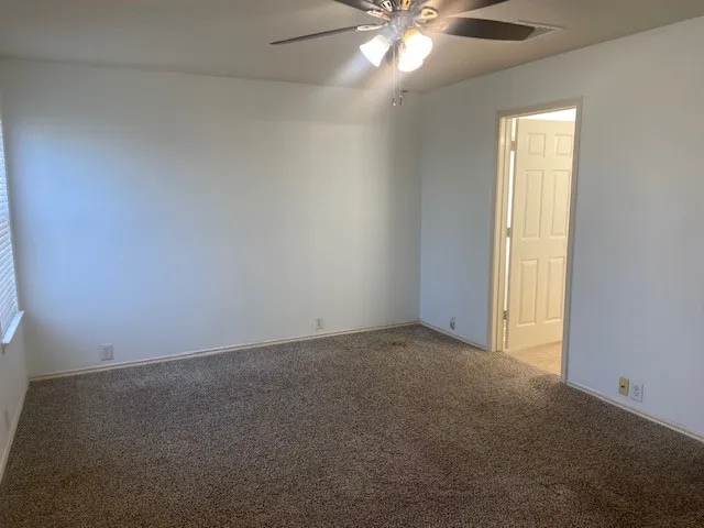 an empty room with a chandelier fan and windows