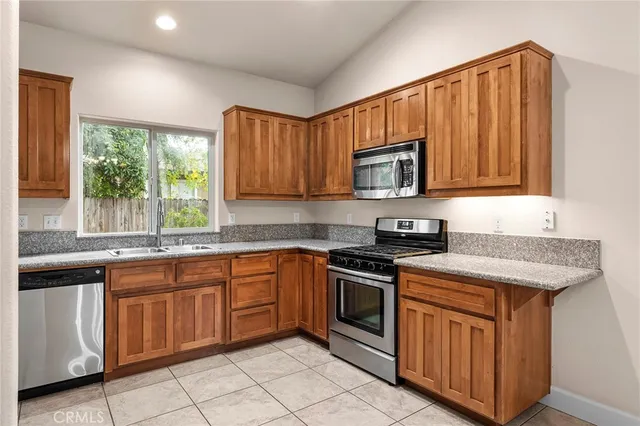 a kitchen with stainless steel appliances granite countertop a stove a sink dishwasher and a microwave oven with cabinets