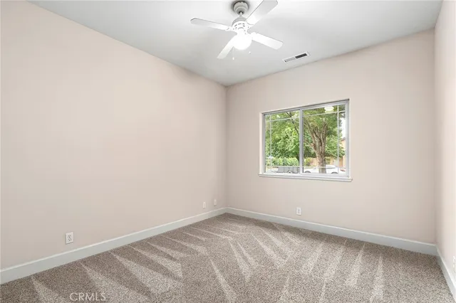 an empty room with a window and a fan