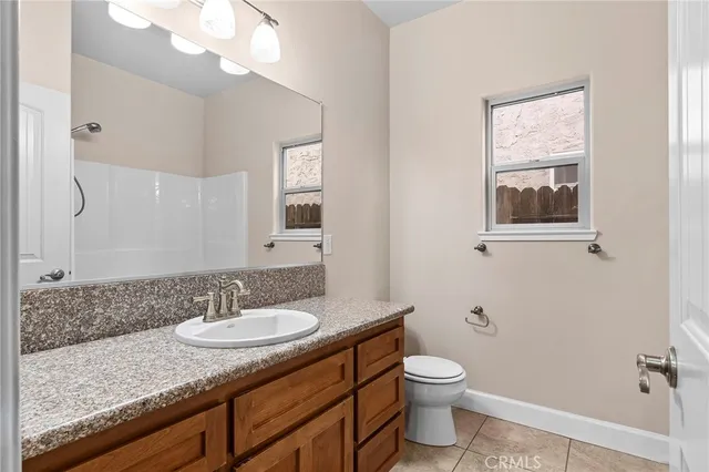 a bathroom with a granite countertop sink toilet and mirror