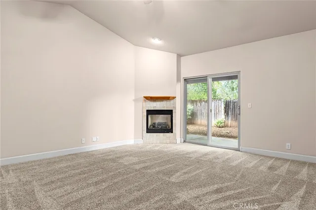 a view of an empty room with a window and fireplace