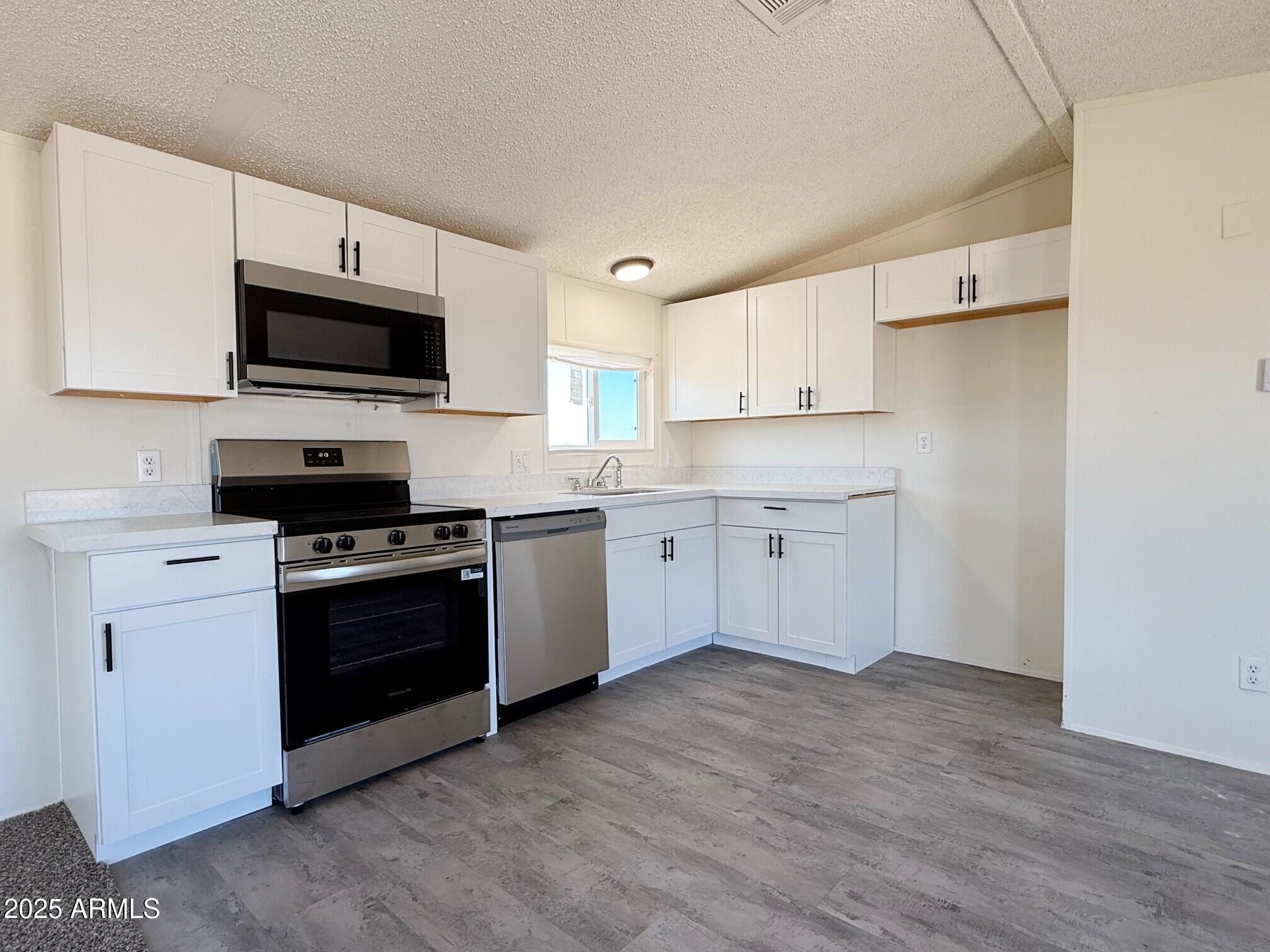 373 South Amarillo Valley Road Maricopa, AZ 85139 - Photo 11 of 23 a kitchen with stainless steel appliances a stove a sink and a microwave