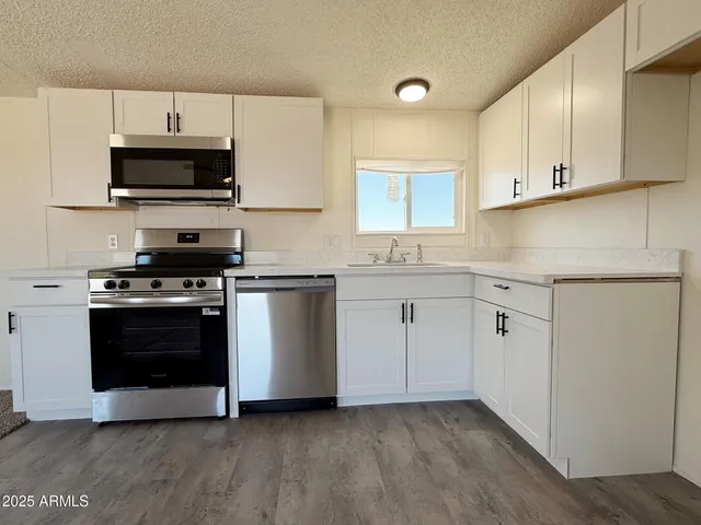 a kitchen with granite countertop white cabinets and stainless steel appliances