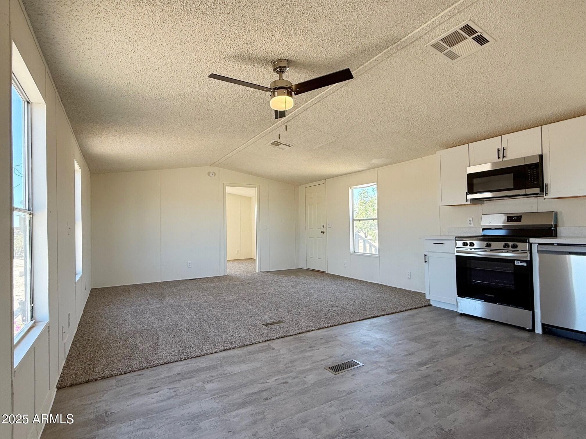 373 South Amarillo Valley Road Maricopa, AZ 85139 - Photo 13 of 23 a view of a kitchen with a stove cabinets and a ceiling fan