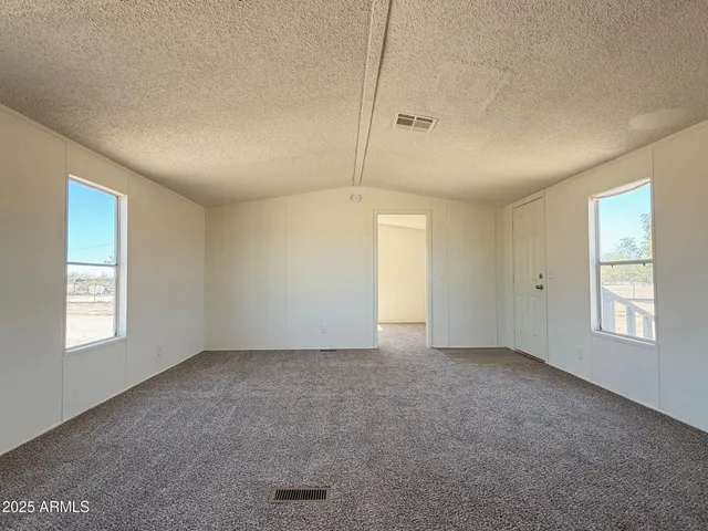 a view of an empty room with window and closet area