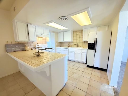 237 Sunset Place Ridgecrest, CA 93555 - Photo 2 of 17 a kitchen with a sink a stove a refrigerator and cabinets