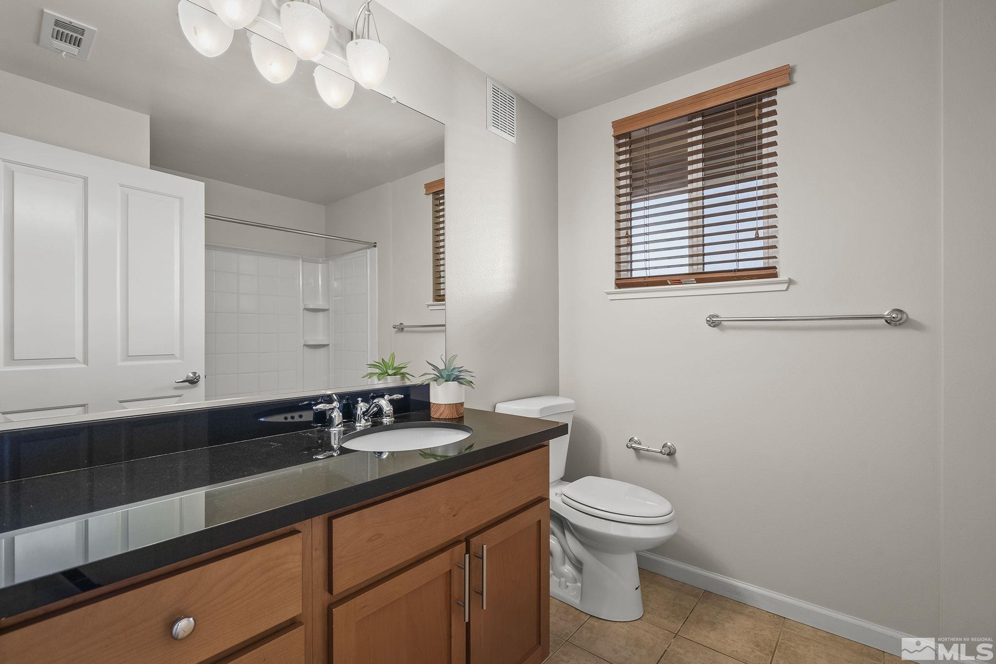 1450 Idlewild Drive, Unit 933 Reno, NV 89509 - Photo 19 of 32 a bathroom with a granite countertop sink a toilet and a mirror