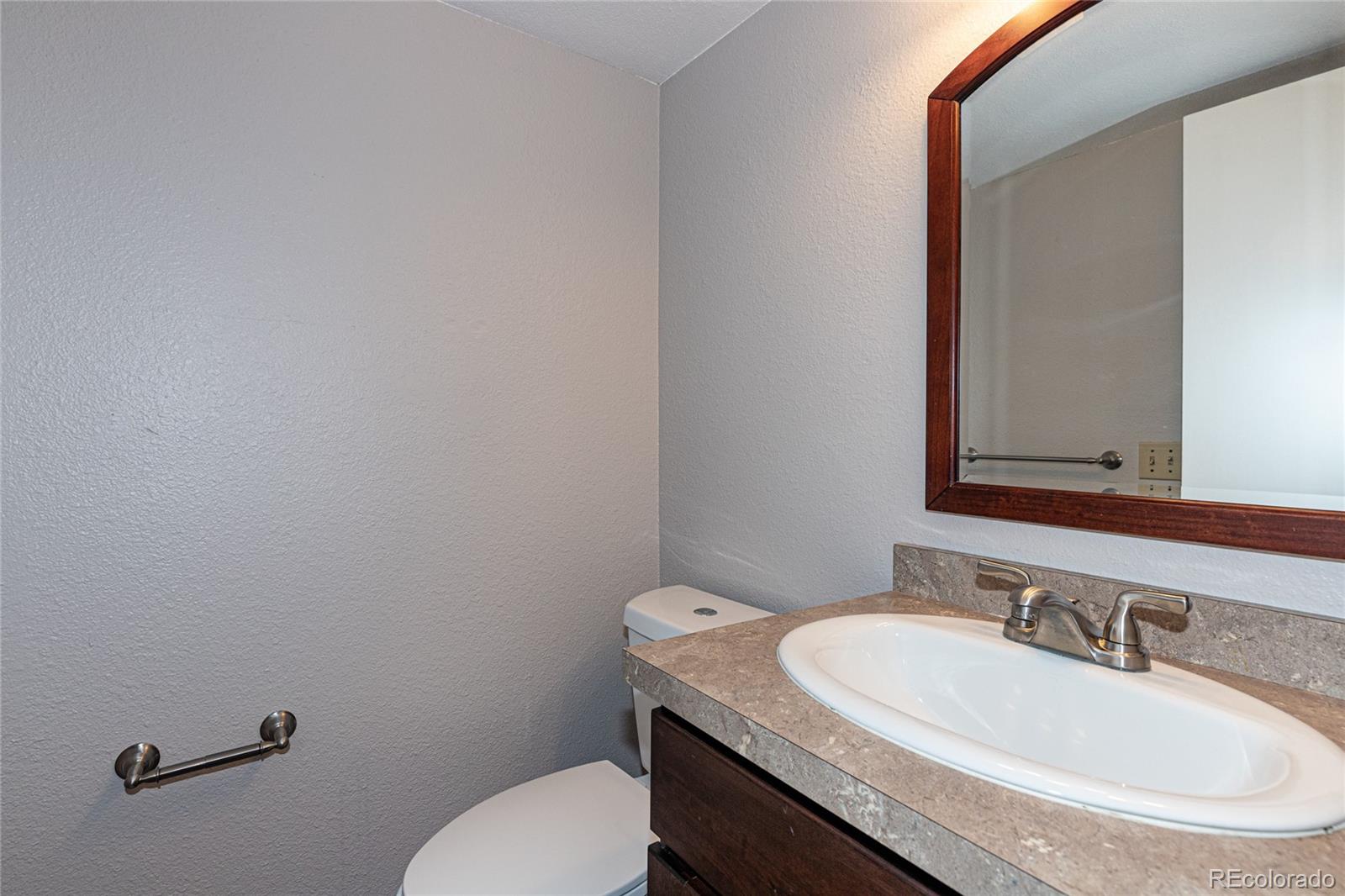 9498 Pendleton Drive Highlands Ranch, CO 80126 - Photo 17 of 28 a bathroom with a granite countertop toilet sink mirror and vanity