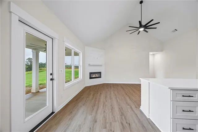 a view of empty room with wooden floor and fan
