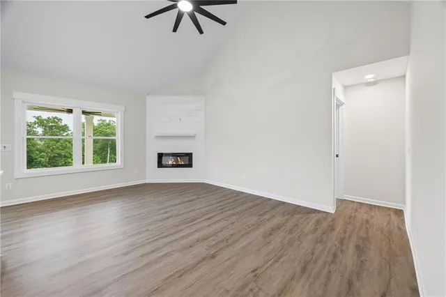 an empty room with wooden floor chandelier fan and windows