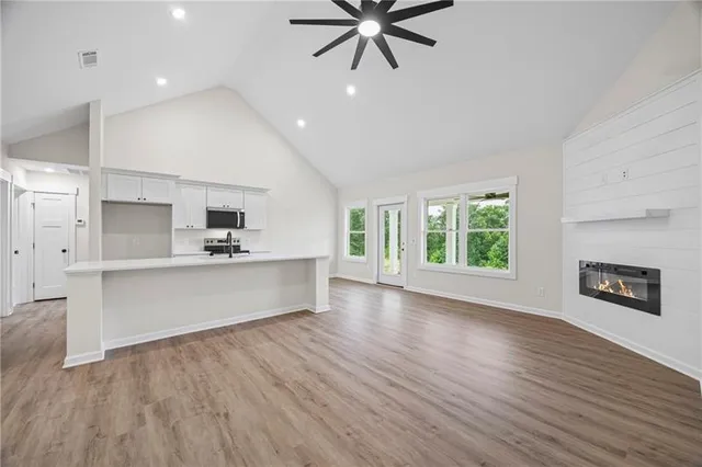 a living room with stainless steel appliances kitchen island hardwood floor and a window