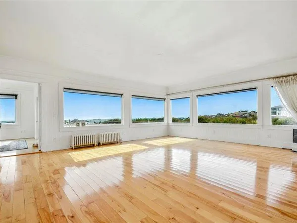 a living room with couches chairs and kitchen view with wooden floor