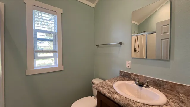 a bathroom with a granite countertop sink toilet a mirror and a window