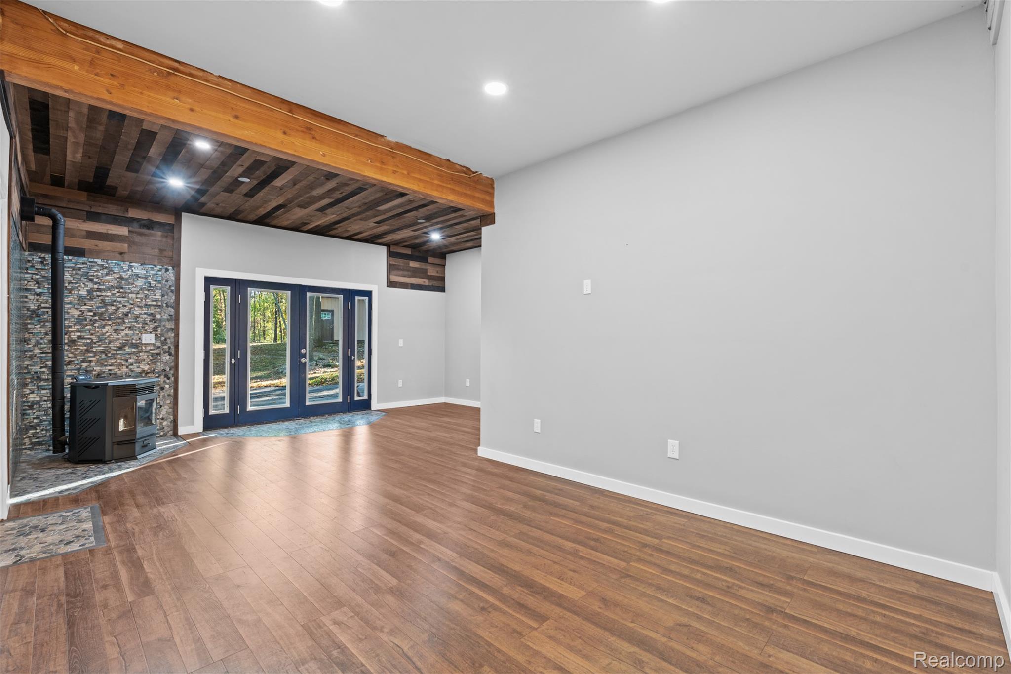 7670 Mi State Road Manchester, MI 48158 - Photo 6 of 53 Unfurnished living room with beamed ceiling, a wood stove, dark wood-type flooring, and recessed lighting