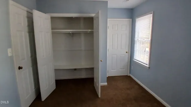 an empty room with closet and windows