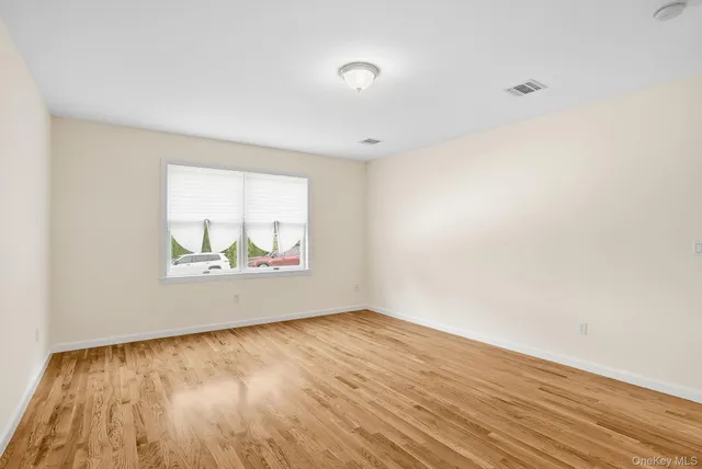 an empty room with wooden floor and window