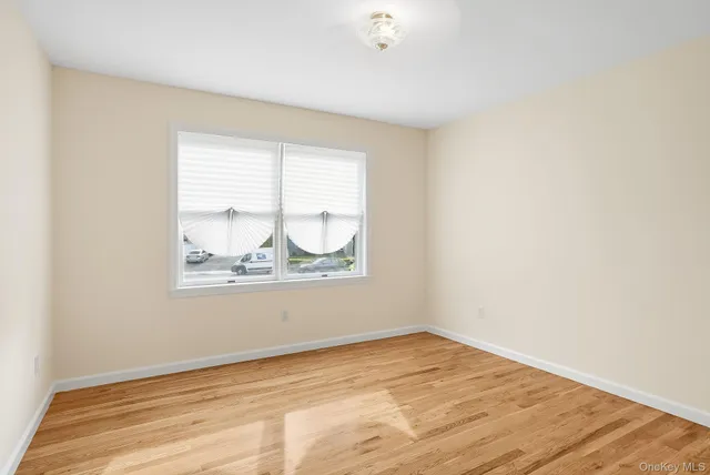 an empty room with wooden floor and window