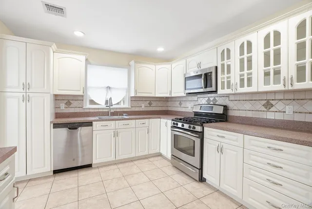 a kitchen with granite countertop white cabinets white appliances sink and window
