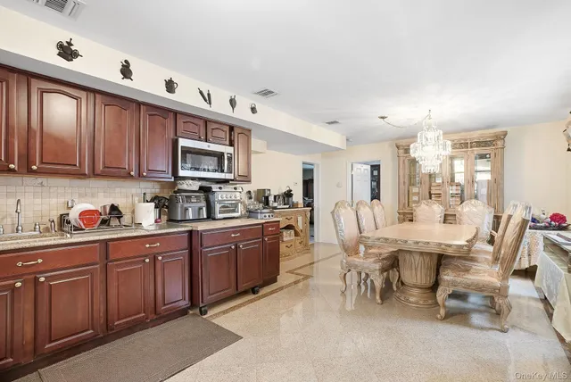 a kitchen with stainless steel appliances granite countertop a table chairs sink and cabinets