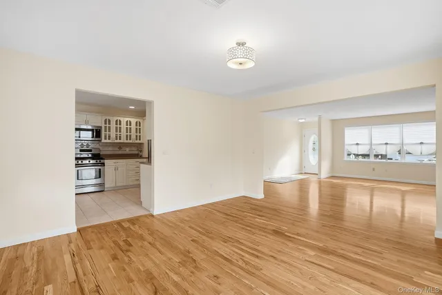 a view of empty room with kitchen and window