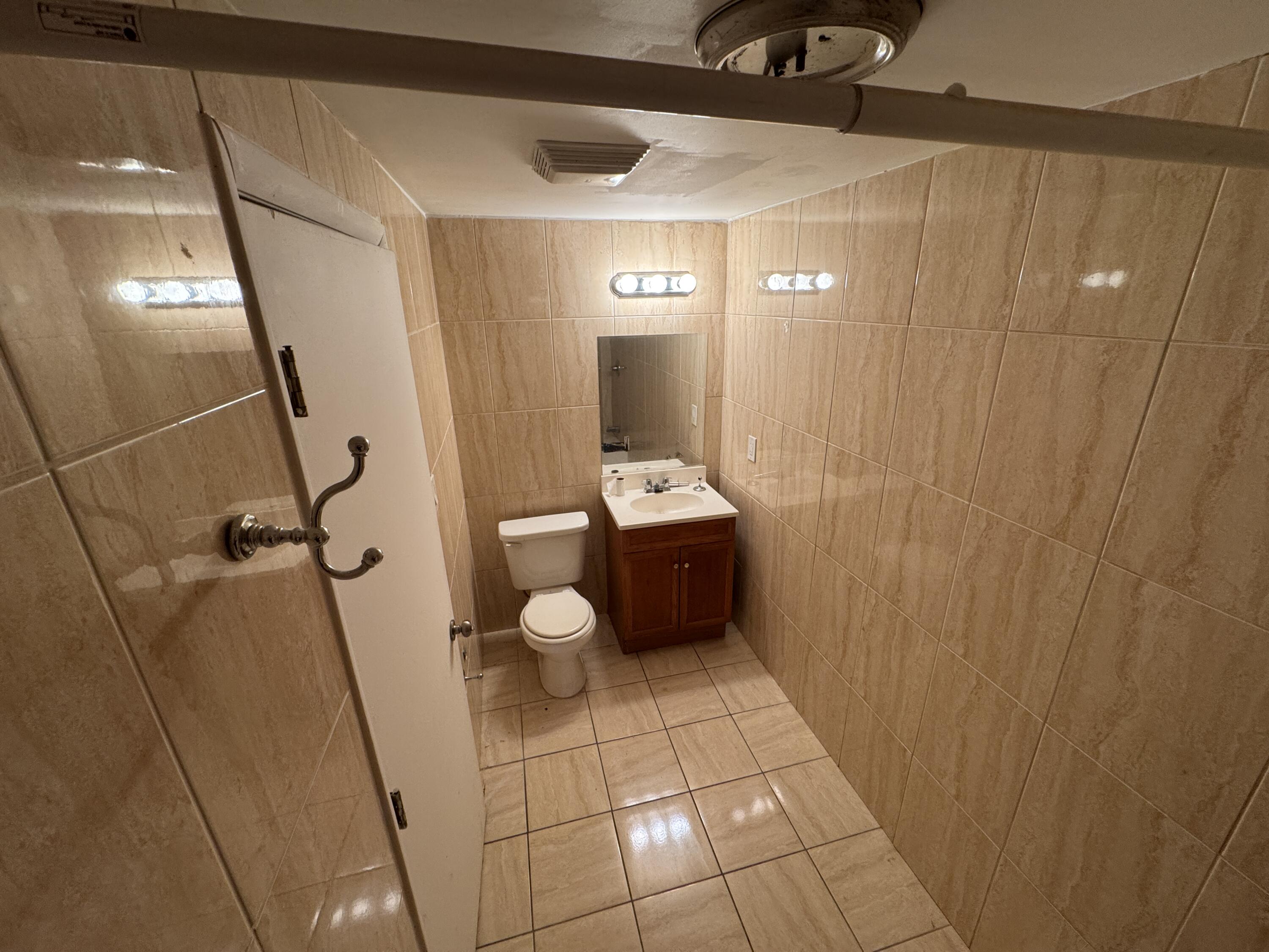 5645 Papaya Road Royal Palm Estates, FL 33413 - Photo 15 of 23 a bathroom with a toilet a sink and mirror