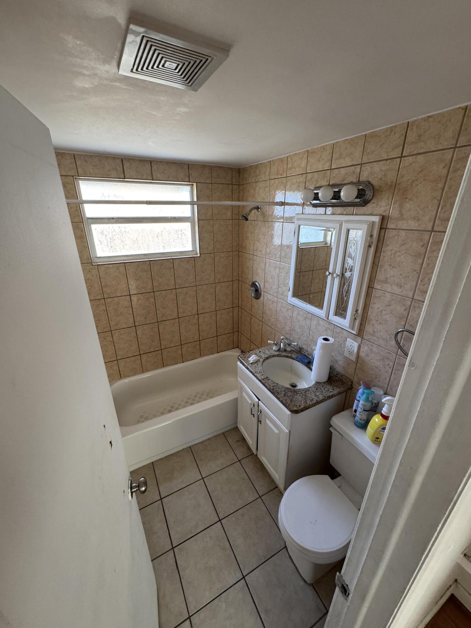 5645 Papaya Road Royal Palm Estates, FL 33413 - Photo 5 of 23 a bathroom with a tub sink toilet and window