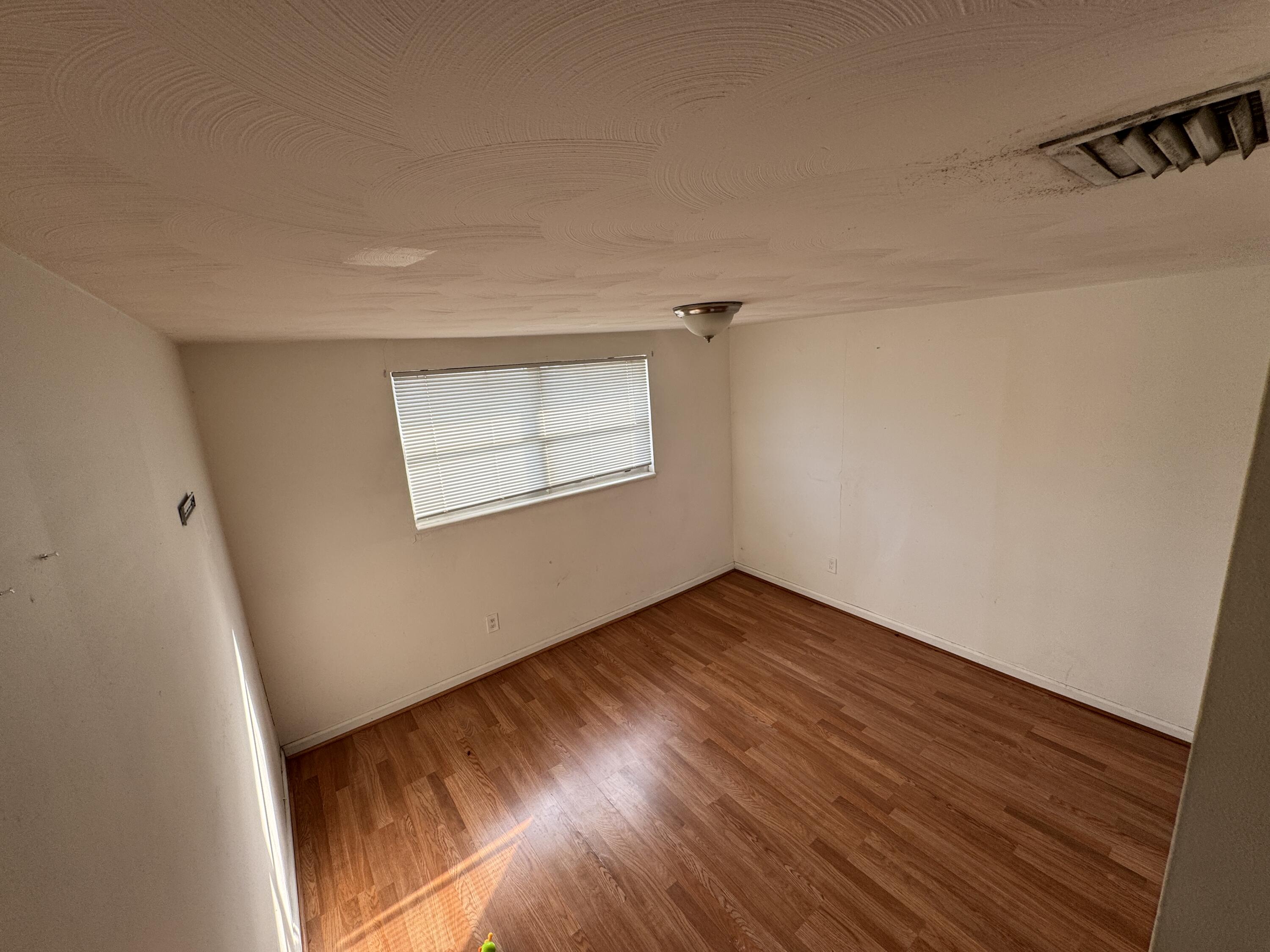5645 Papaya Road Royal Palm Estates, FL 33413 - Photo 10 of 23 a view of an empty room with wooden floor and a window
