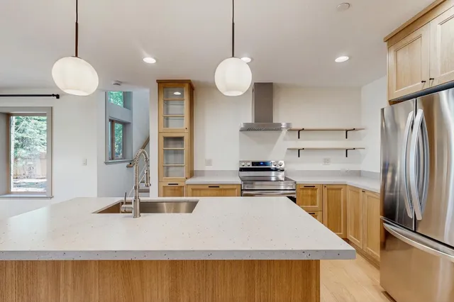 a kitchen with stainless steel appliances granite countertop a sink a stove and a refrigerator